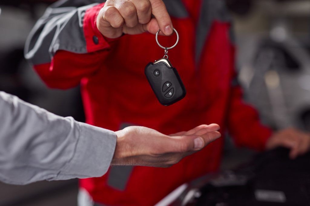 Car mechanic passing car keys to client